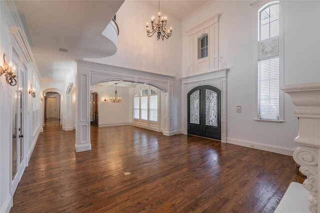 foyer featuring a notable chandelier, dark wood-style floors, french doors, arched walkways, and crown molding