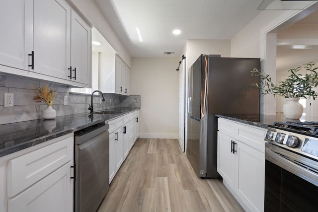 kitchen with tasteful backsplash, stainless steel appliances, light wood-style floors, a sink, and baseboards
