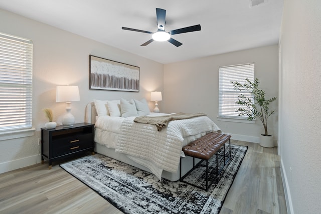 bedroom with multiple windows, light wood-style flooring, and baseboards
