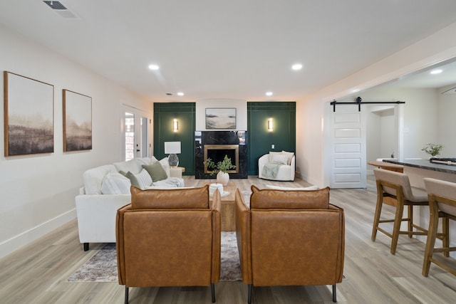 living room with visible vents, a barn door, light wood finished floors, and baseboards