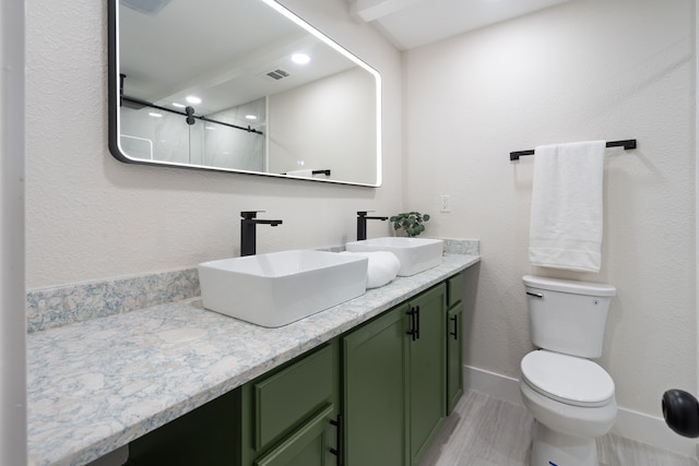 bathroom with a shower, toilet, double vanity, and a sink