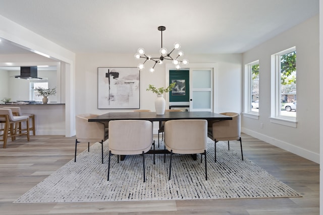 dining area with baseboards, wood finished floors, and a notable chandelier