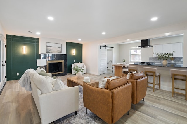 living room featuring a barn door, light wood-style floors, and recessed lighting