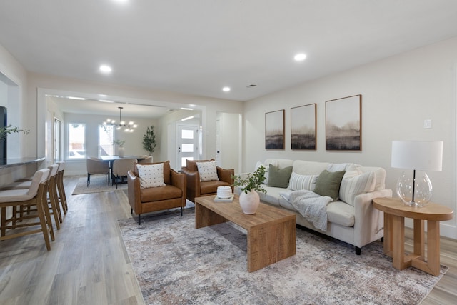 living room with baseboards, recessed lighting, an inviting chandelier, and light wood finished floors