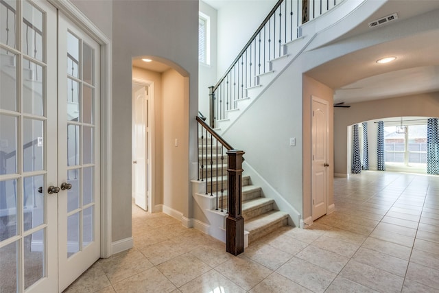 816 Sandbox Dr, Little Elm, TX 76227 - stairs featuring arched walkways, tile patterned floors, french doors, baseboards, and a towering ceiling