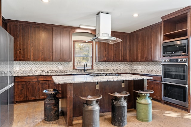 kitchen featuring light wood finished floors, a kitchen island, appliances with stainless steel finishes, and island exhaust hood