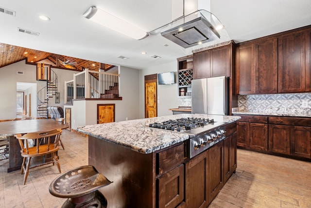 kitchen featuring a kitchen island, visible vents, stainless steel appliances, and decorative backsplash