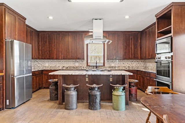 kitchen featuring tasteful backsplash, appliances with stainless steel finishes, a center island, and extractor fan