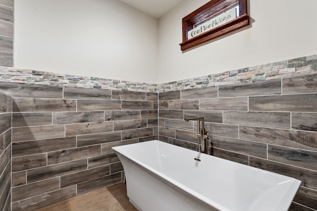 bathroom featuring wainscoting, tile walls, and a freestanding tub