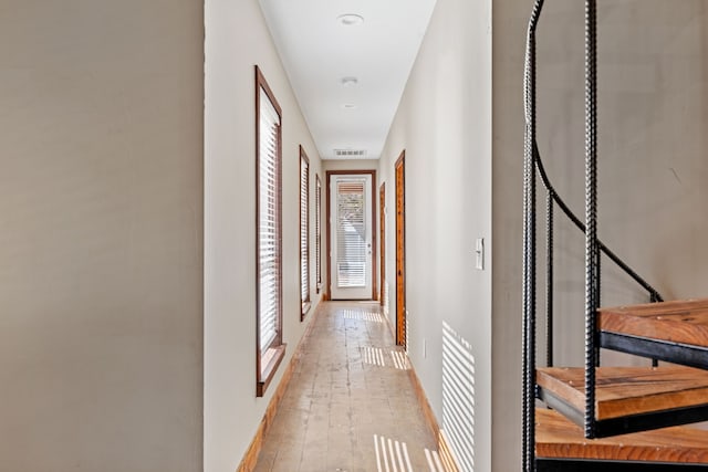 corridor with visible vents, baseboards, and light wood-style floors