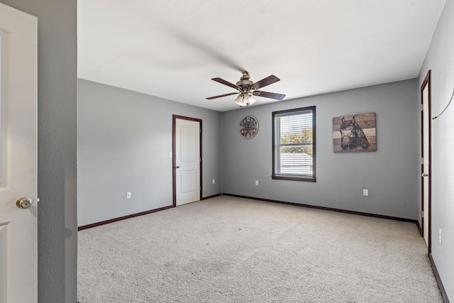 unfurnished room with light colored carpet, baseboards, and a ceiling fan