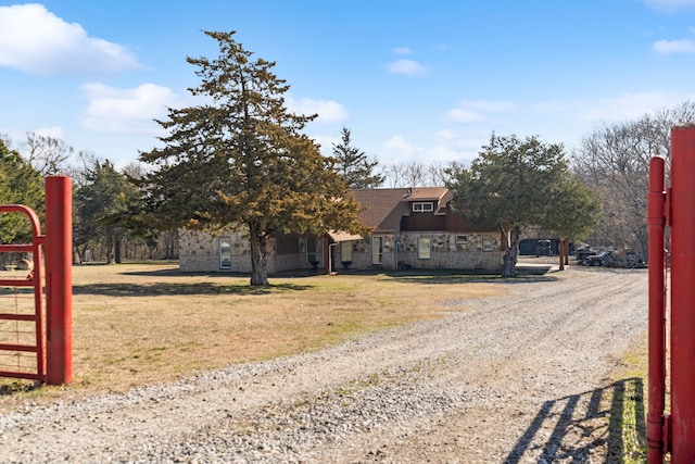 view of front of home with a front lawn, stone siding, driveway, and roof with shingles