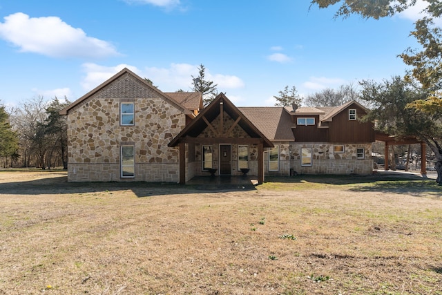view of front of property with a front yard, stone siding, and roof with shingles