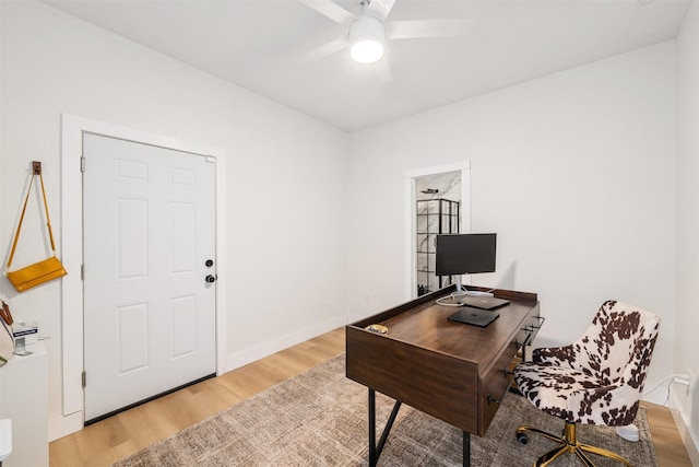 office area with baseboards, light wood-style floors, and a ceiling fan