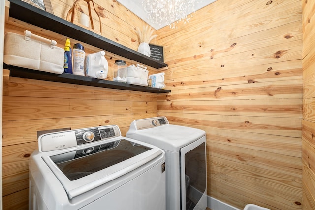 clothes washing area featuring laundry area, a notable chandelier, and separate washer and dryer