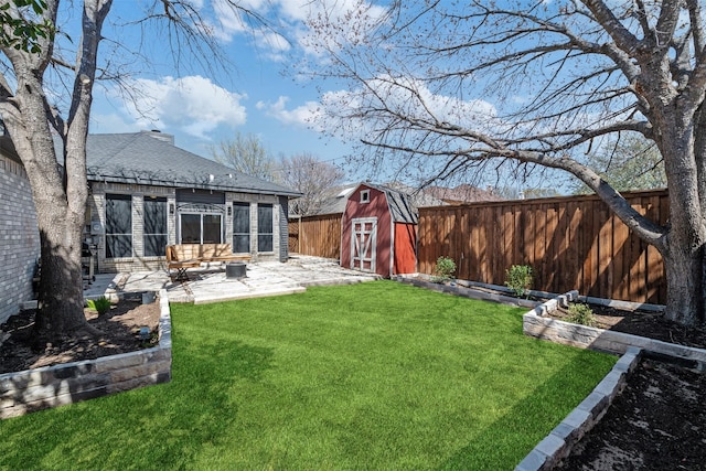 view of yard with a storage unit, an outbuilding, a fenced backyard, and a patio area