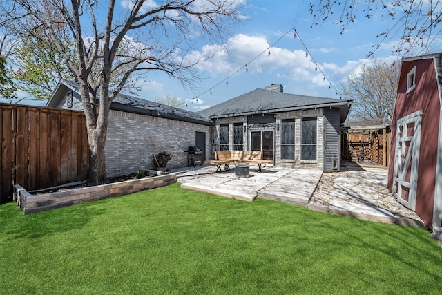 rear view of house featuring a yard, a patio, roof with shingles, and a fenced backyard
