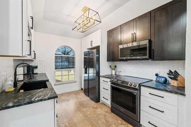 kitchen with a sink, dark stone countertops, stainless steel appliances, decorative backsplash, and dark brown cabinets