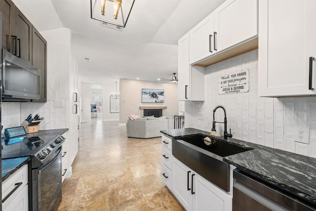 kitchen featuring black electric range oven, a sink, stainless steel dishwasher, dark stone counters, and ceiling fan
