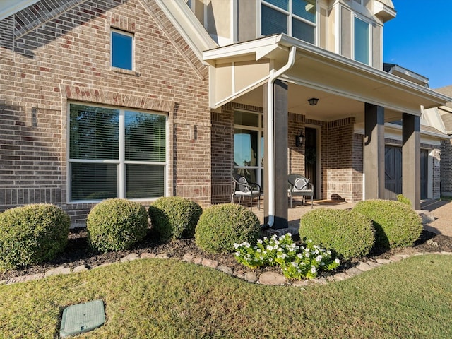 view of exterior entry with brick siding and covered porch