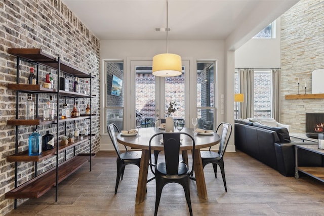 dining space featuring a stone fireplace, a dry bar, and wood finished floors