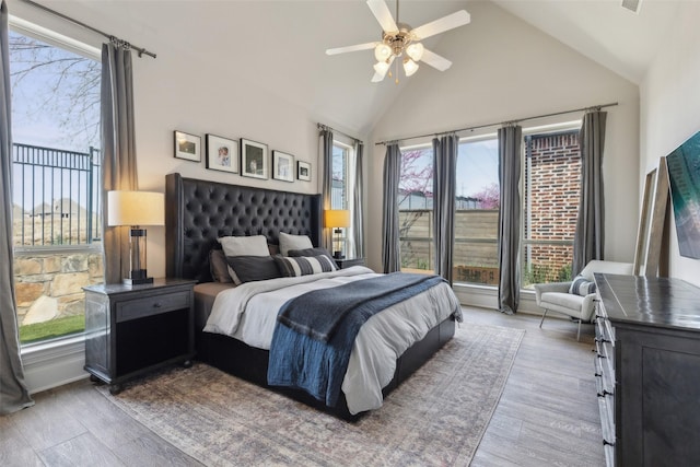bedroom with high vaulted ceiling, multiple windows, ceiling fan, and wood finished floors