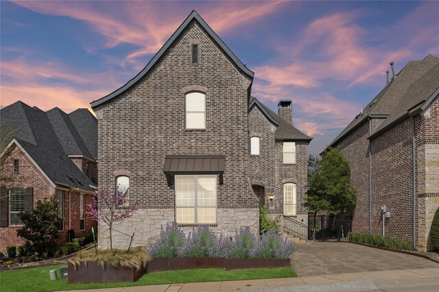french country home with brick siding and stone siding