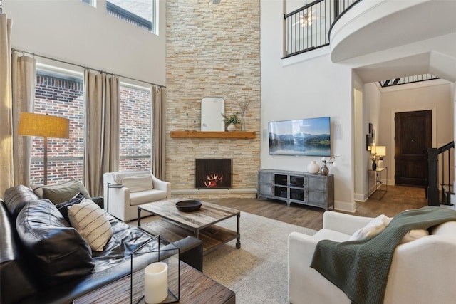living room featuring baseboards, wood finished floors, a towering ceiling, and a fireplace