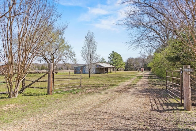 view of road featuring a rural view, a gated entry, dirt driveway, and a gate