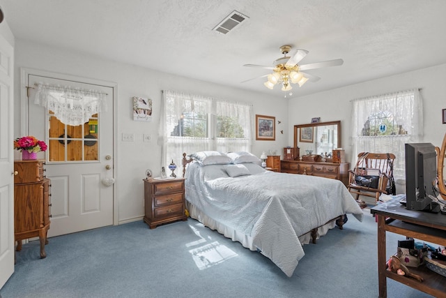 bedroom with visible vents, carpet, ceiling fan, and a textured ceiling