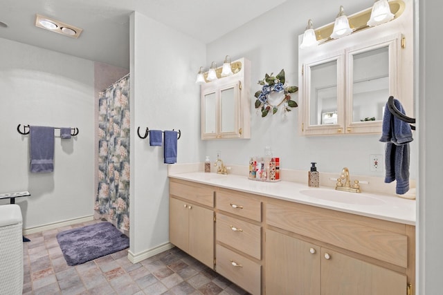 bathroom featuring a sink, stone finish flooring, baseboards, and double vanity