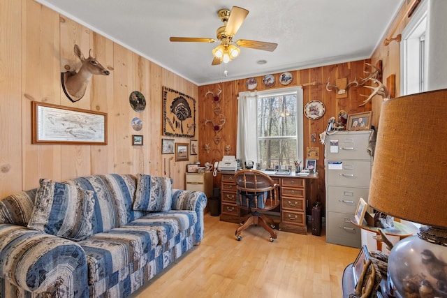 office featuring crown molding, a ceiling fan, wood walls, and light wood finished floors