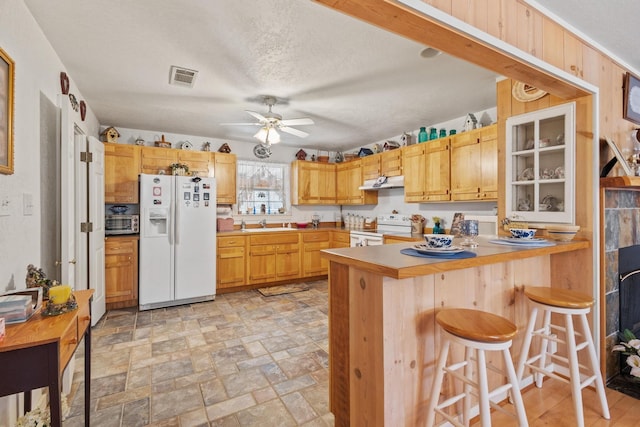 kitchen with visible vents, a ceiling fan, under cabinet range hood, white appliances, and a peninsula