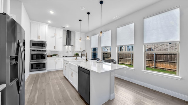 1017 Wrenwood Dr, Justin, TX 76247 - kitchen featuring light wood finished floors, tasteful backsplash, wall chimney range hood, light countertops, and appliances with stainless steel finishes