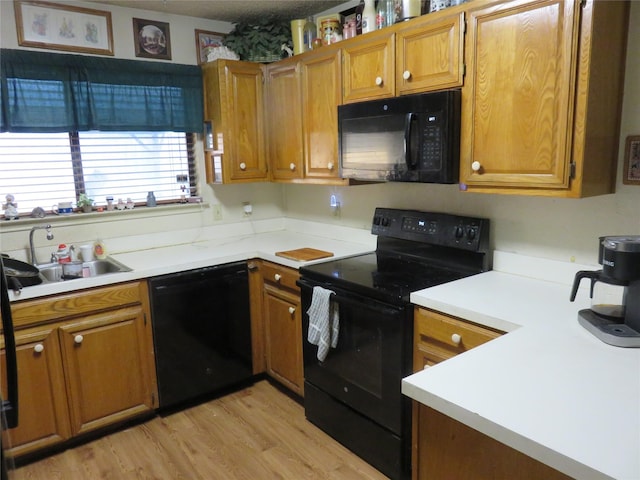 313 Conger Dr, Mesquite, TX 75149 - kitchen with brown cabinetry, light wood finished floors, a sink, and black appliances