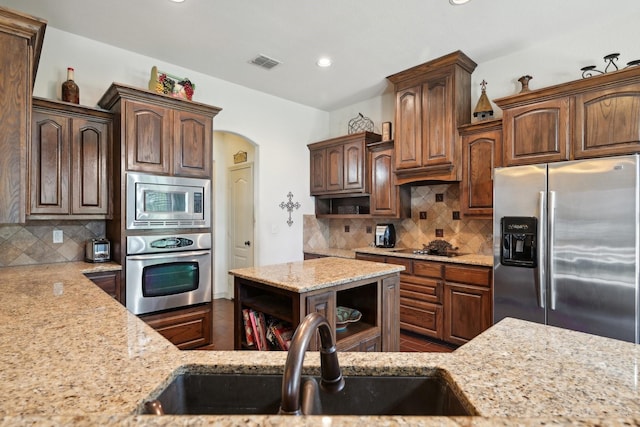 kitchen with visible vents, open shelves, a sink, stainless steel appliances, and backsplash