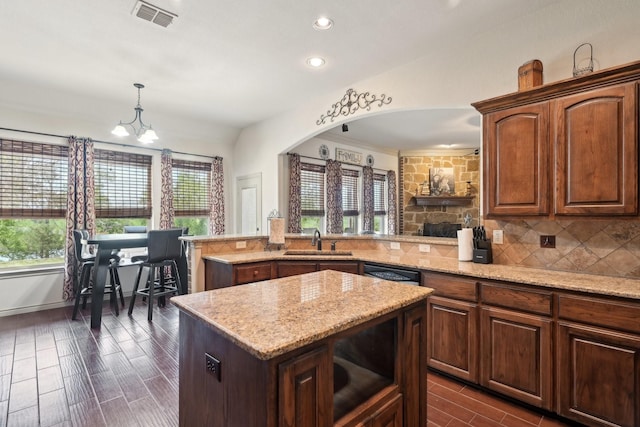 kitchen featuring tasteful backsplash, a center island, visible vents, dishwashing machine, and a sink
