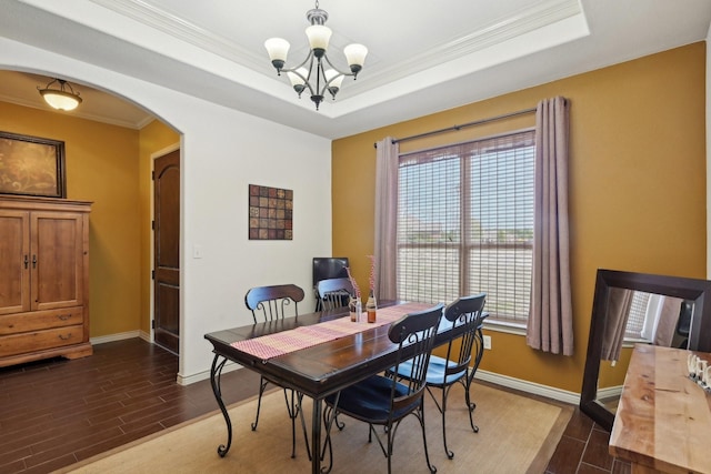 dining space featuring a tray ceiling, arched walkways, an inviting chandelier, and wood tiled floor