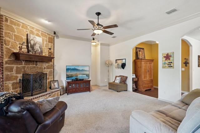 carpeted living area with crown molding, visible vents, a ceiling fan, and arched walkways
