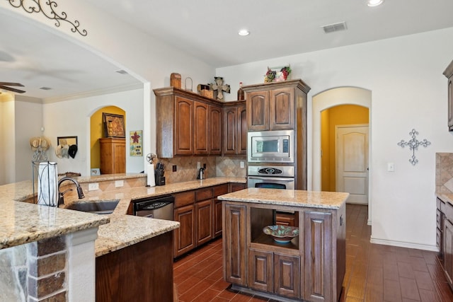 kitchen featuring stainless steel appliances, arched walkways, light stone countertops, and a sink