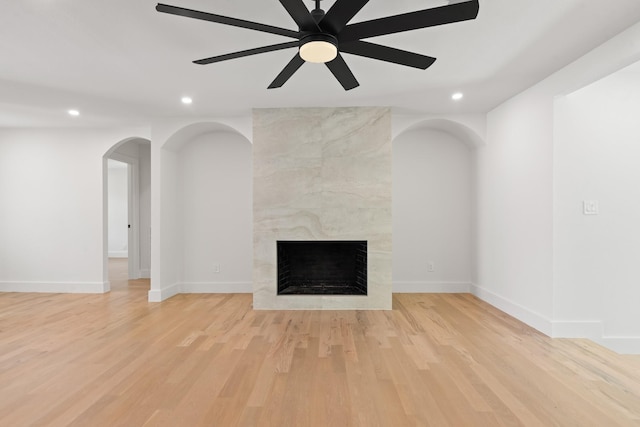 9805 Bluff Dale Dr, Dallas, TX 75218 - unfurnished living room featuring a premium fireplace, arched walkways, light wood-style floors, and recessed lighting