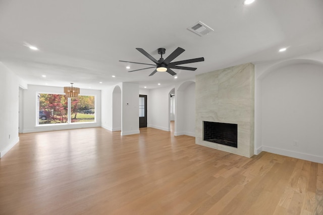 9805 Bluff Dale Dr, Dallas, TX 75218 - unfurnished living room with visible vents, arched walkways, light wood-style floors, recessed lighting, and a premium fireplace
