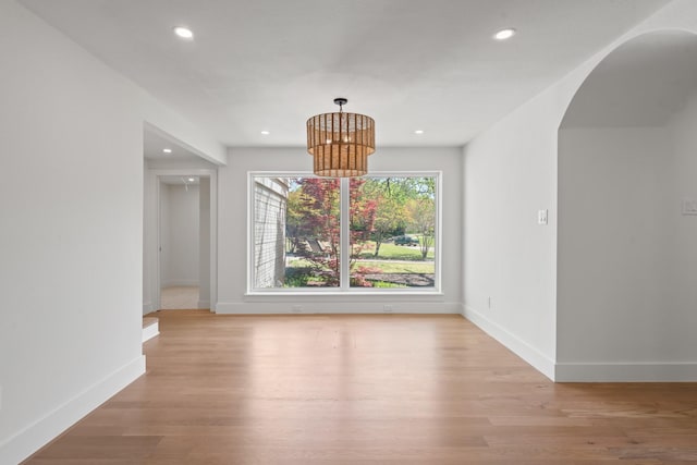 9805 Bluff Dale Dr, Dallas, TX 75218 - unfurnished dining area with baseboards, arched walkways, a notable chandelier, and light wood-style floors