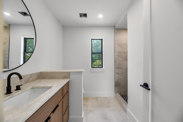 9805 Bluff Dale Dr, Dallas, TX 75218 - bathroom featuring tiled shower, vanity, baseboards, and recessed lighting