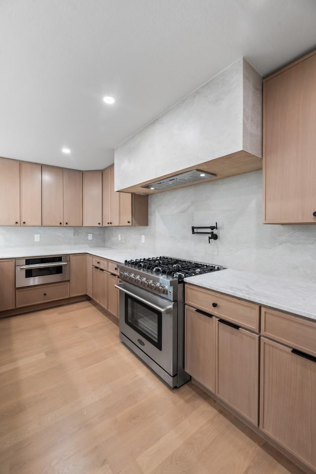9805 Bluff Dale Dr, Dallas, TX 75218 - kitchen featuring light wood-style flooring, decorative backsplash, high end range, and light brown cabinetry