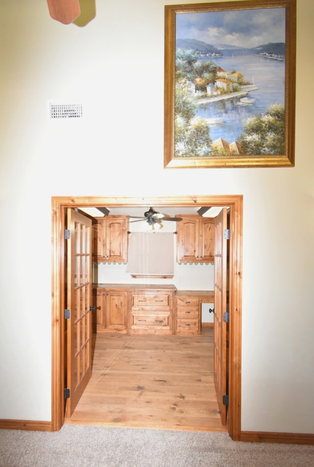 kitchen with light brown cabinetry, visible vents, baseboards, and ceiling fan