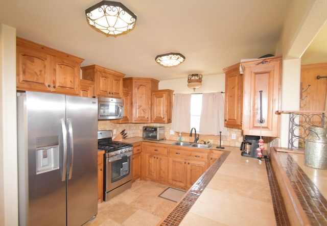 kitchen with tasteful backsplash, appliances with stainless steel finishes, light countertops, and a sink
