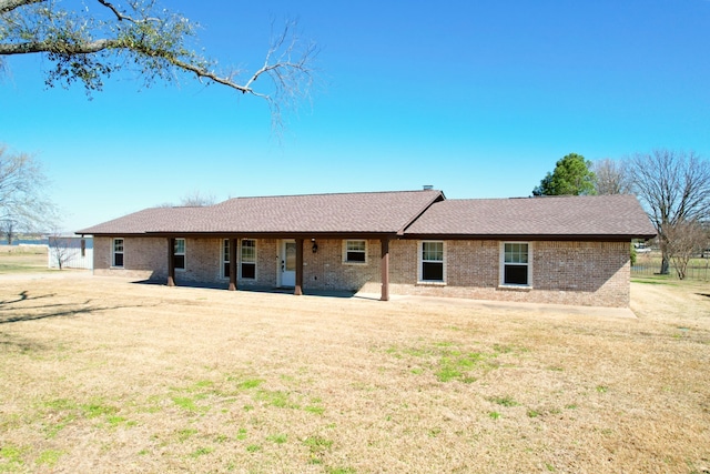 back of house featuring a yard, brick siding, and a shingled roof