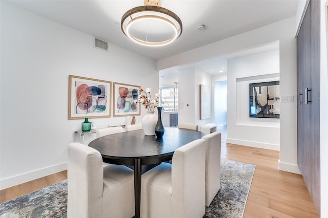 3130 N Harwood St Unit 1404, Dallas, TX 75201 - dining area featuring light wood-style floors, baseboards, and a chandelier