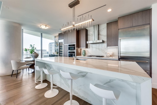 3130 N Harwood St Unit 1404, Dallas, TX 75201 - kitchen featuring wall chimney exhaust hood, built in refrigerator, a sink, a center island with sink, and modern cabinets